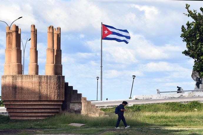 Archivo - Arquivo - HAVANA, 30 de outubro de 2025 — Um pedestre passa por uma bandeira nacional cubana em Havana, capital de Cuba, em 29 de outubro de 2025. A Assembleia Geral das Nações Unidas (AGNU) aprovou na quarta-feira um projeto de resolução instan
