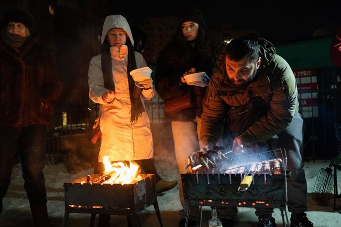 Un grup de veïns del barri de Pozniaki, a Kíiv, prepara una barbacoa, enmig dels talls de llum provocats pels atacs de Rússia.