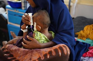 Archivo - Una madre sostiene a su hijo con desnutrición, al que alimenta con una jeringa en el Hospital Regional de Bay (Somalia) al que da apoyo MSF.