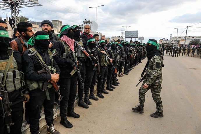 Archivo - Arquivo - 08 de fevereiro de 2025, Territórios Palestinos, Deir al-Balah: Combatentes das brigadas Ezz al-Din Al-Qassam, ala militar do Hamas, formam um corredor enquanto reféns israelenses são entregues a representantes do Comitê Internacional 