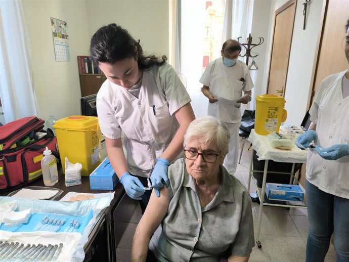 Una enfermera vacuna de la gripe a una mujer.