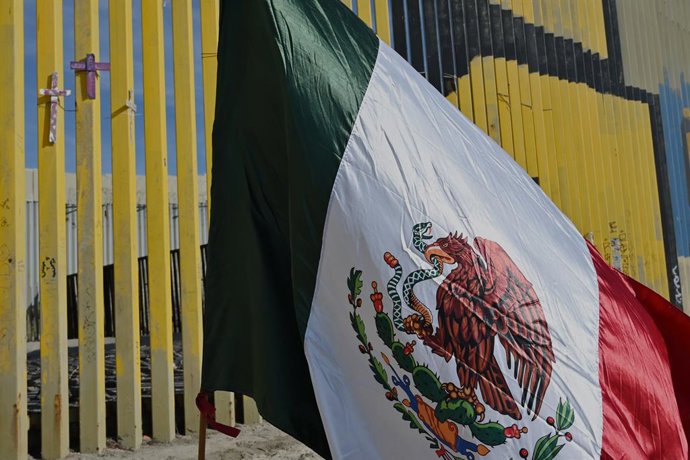 Archivo - Arquivo - 18 de dezembro de 2025, Tijuana, Baja California, México: Cruzes com uma bandeira do México no muro da fronteira entre os EUA e o México em Tijuana, Baja California, México, em memória dos migrantes que morreram ao cruzar a fronteira, 