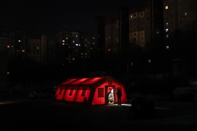 Una tienda móvil iluminada con el telón de fondo de una zona residencial a oscuras durante un corte de electricidad en Ucrania.