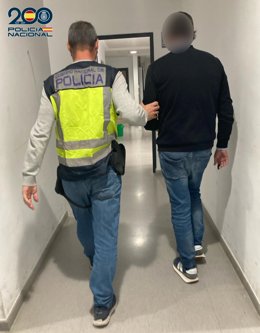 Un agente de la Policía Nacional custodia a un detenido por  su implicación en un presunto delito de estafa cometido en Guinea.