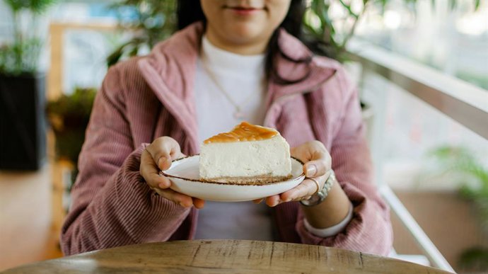 Una mujer sostiene un plato con un trozo de pastel