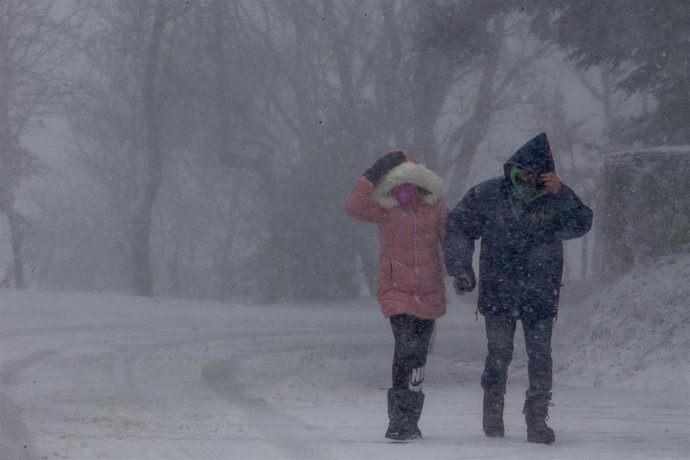 Archivo - Un hombre y una mujer se protegen del temporal, a 27 de noviembre de 2021, en Pedrafita do Cebreiro, Lugo, Galicia (España). 