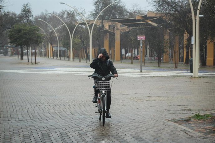 Archivo - Un ciclista se protege de la lluvia y del viento