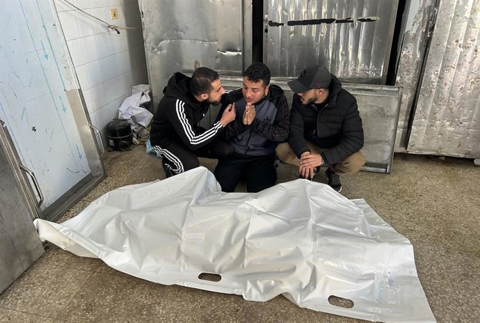 Palestinos junto ao cadáver de um homem morto por tiros do Exército de Israel no campo de refugiados de Al Bureij, no centro da Faixa de Gaza, apesar do cessar-fogo em vigor desde 10 de outubro de 2025 (arquivo)