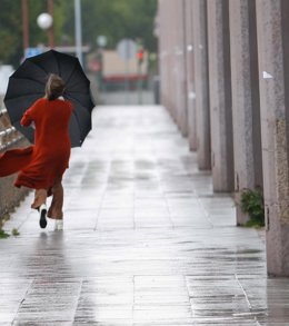 Archivo - Imagen de archivo de viandante por el puente de San Telmo en Sevilla en una mañana de tormentas y lluvias.
