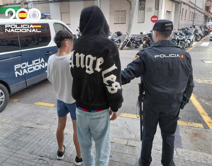 Los dos detenidos, de espaldas y junto a un agente de la Policía Nacional.