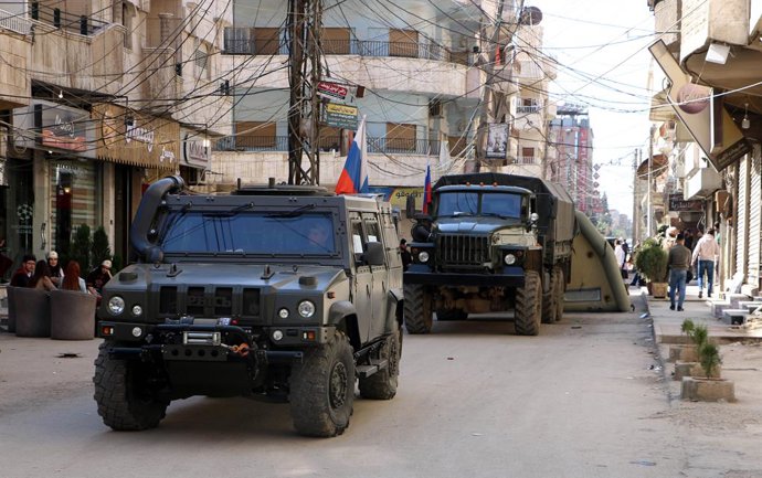 Archivo - Arquivo - 08 de março de 2020, Síria, Qamishli: Veículos da polícia militar russa montam guarda do lado de fora de um posto médico móvel russo, onde médicos russos tratam sírios na cidade de Qamishli, no norte da Síria, na fronteira entre a Síri