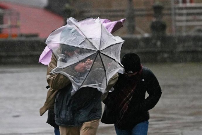 Varias personas intentan sujetar sus paraguas, a 26 de enero de 2026, en Santiago de Compostela.