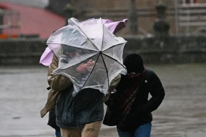 Varias personas intentan sujetar sus paraguas, a 26 de enero de 2026, en Santiago de Compostela.