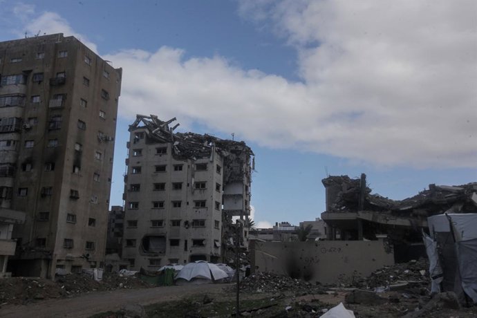13 de janeiro de 2026, Gaza, Palestina: (INT) Palestinos caminham na chuva enquanto famílias se abrigam sob prédios inseguros em Gaza. 13 de janeiro de 2026 — Gaza, Palestina: Palestinos foram vistos caminhando pela cidade de Gaza sob forte chuva, enquant