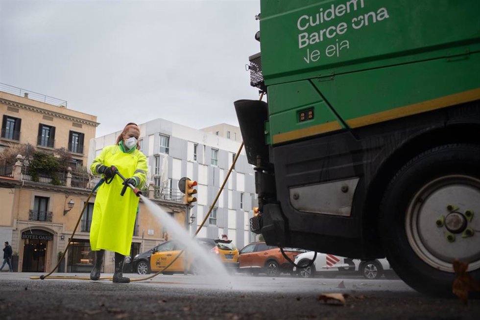 Archivo - Una trabajadora de la limpieza riega una calle con una manguera