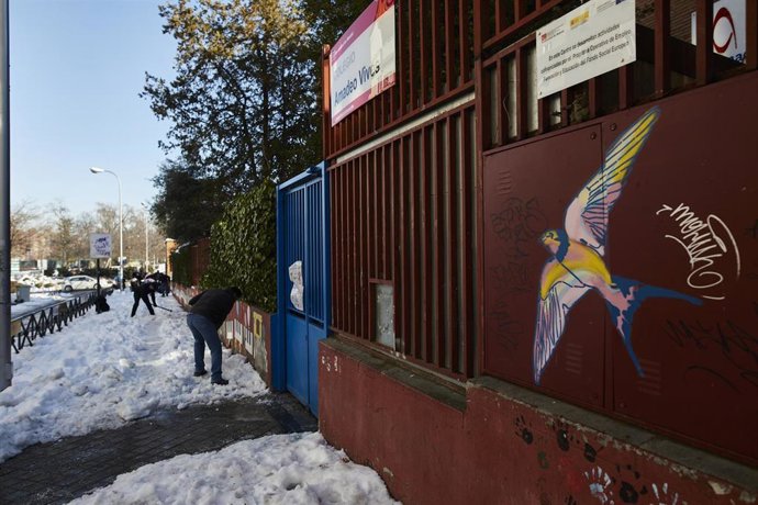 Archivo - Varios familiares colaboran en la limpieza del hielo y la nieve en las inmediaciones del colegio Amadeo Vives, en Madrid, (España), a 16 de enero de 2021. 