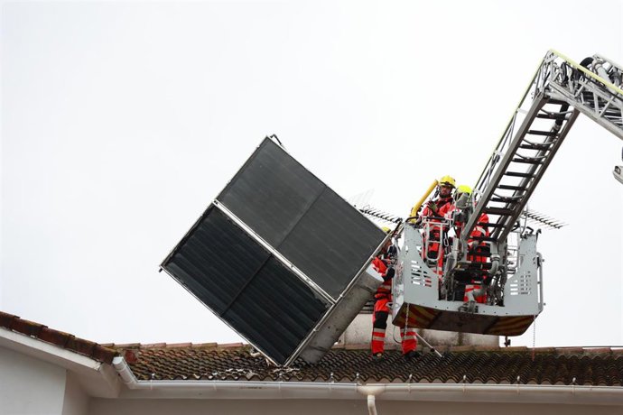 Bomberos de Sevilla proceden a retirar un panel solar que las fuertes rachas de viento, del temporal que barre a toda la provincia, ha desprendido de sus anclajes, en la calle Telémaco de Sevilla Este. 