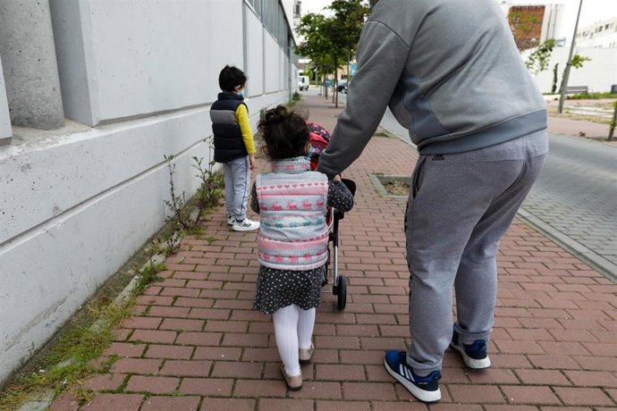 Archivo - Dos niños pasean por la calle junto a su padre. En Madrid (España) a 27 de abril de 2020.