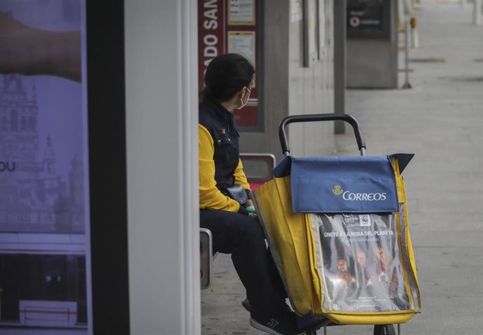Archivo - Una trabajadora de correos en una parada de autobús.