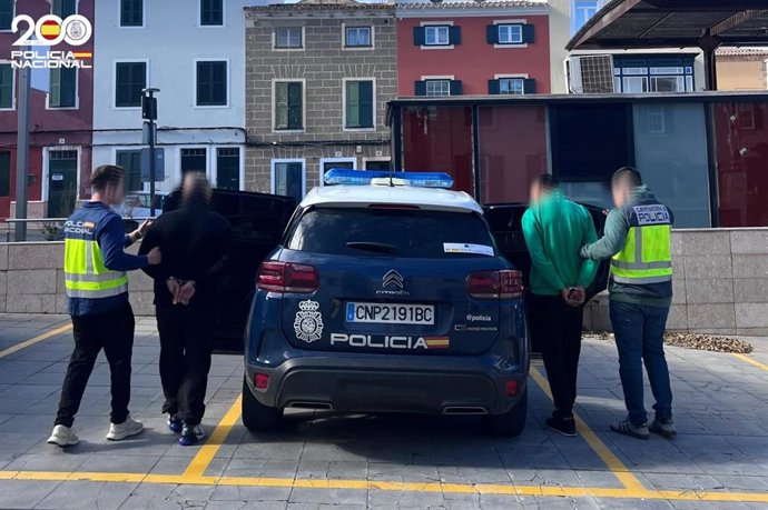 Agentes de la Policía Nacional con los detenidos en un coche patrulla.