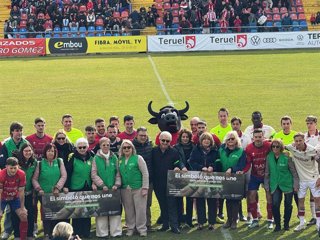 La consejera y candidata del PP, Tomasa Hernández y  la alcaldesa de Teruel, Emma Buj, ambas en el centro del césped de Pinilla junto a los jugadores del CD Teruel y el Real Murcia este domingo.