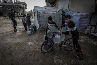 28 January 2026, Palestinian Territories, Khan Younis: Palestinian children transport gallons of drinking water they filled from a water truck in Khan Younis. Palestinians in Gaza are suffering from a severe water crisis due to the destruction of water we
