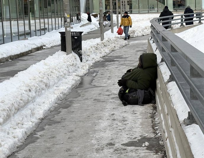 January 27, 2026, Staten Island, New York, USA: A homeless man sits on the ground surrounded by snow outside of the Staten Island Ferry terminal in Staten Island. At least 10 people have died after being exposed to the bitter cold that has persisted in Ne