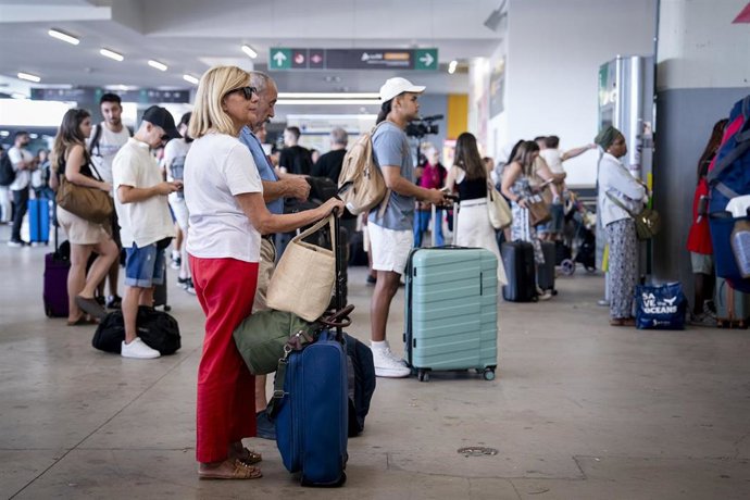 Archivo - Varias personas esperan con maletas y observan los carteles de salidas, en la estación de Chamartín Clara Campoamor, a 14 de agosto de 2025, en Madrid (España)