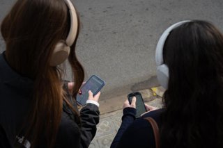 Archivo - Dos chicas usan el teléfono móvil.