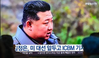 Archivo - Dos personas observan una retransmisión de televisión en la que se puede ver al líder norcoreano Kim Jong Un