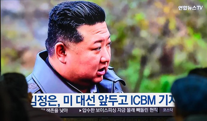 Archivo - Dos personas observan una retransmisión de televisión en la que se puede ver al líder norcoreano Kim Jong Un