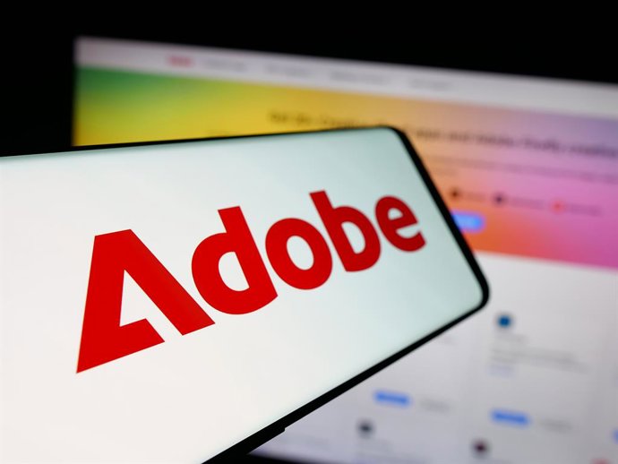 Archivo - Arquivo - 15 de outubro de 2025, Alemanha: Nesta ilustração fotográfica, um smartphone com o logotipo da empresa de software norte-americana Adobe Inc. é visto na tela em frente ao site.