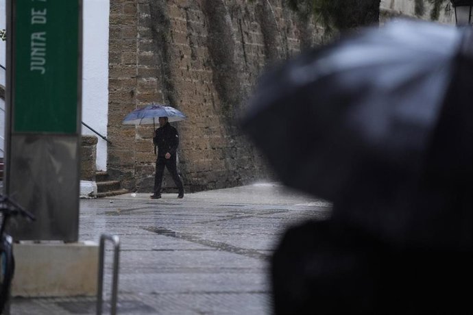 Archivo - Transeuntes bajo sus paraguas en una de las jornadas de lluvia en Cádiz.