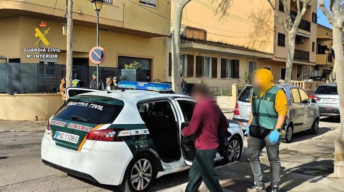 Uno de los arrestados entra en una patrulla de la Guardia Civil escoltado por un agente.