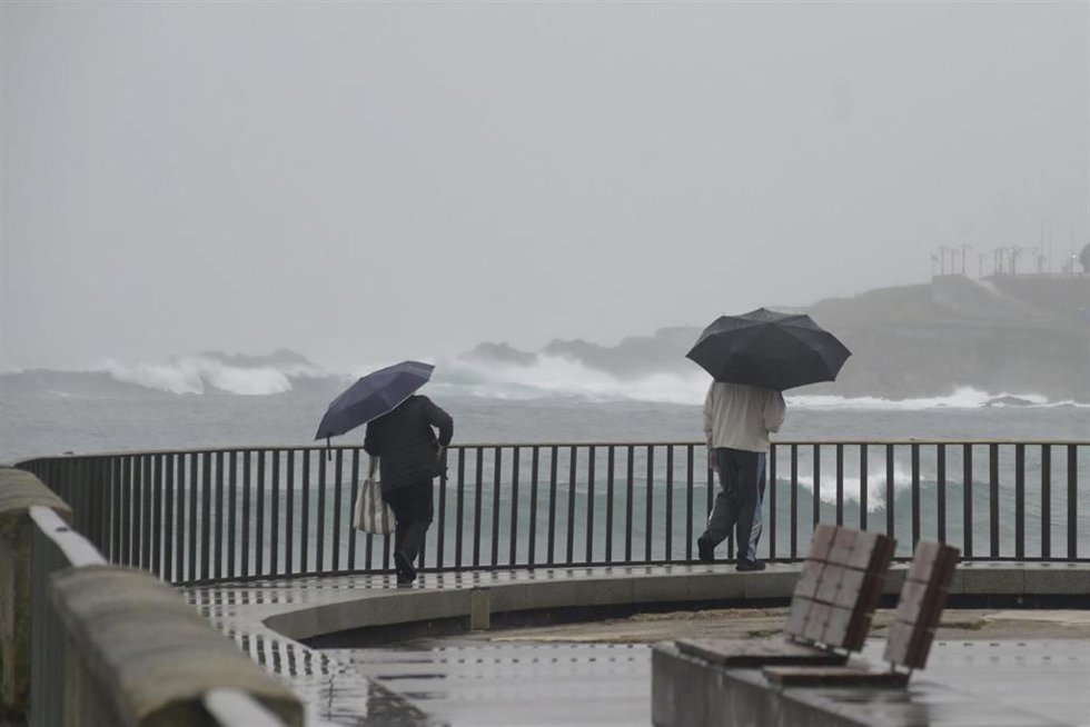 Archivo - Dos personas caminan con un paraguas al lado de la playa del Orzán, a 22 de enero de 2024, A Coruña, Galicia (España). La dirección xeral de Emerxencias de la Xunta ha activado hoy la alerta naranja por temporal costero en todo el litoral gall