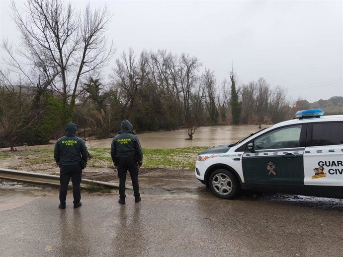 Dos agentes de la Guardia Civil observan una vía afectada por el agua en la provincia de Jaén.