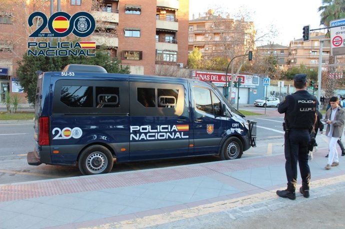 Un agente junto a un vehículo de Policía Nacional.