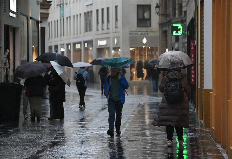 Transeúntes por céntricas calles de Sevilla se protegen de la lluvia que la borrasca Leonardo deja a su paso. A 4 de febrero de 2026, en Sevilla (Andalucía, España).