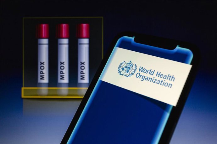 Archivo - 14 August 2024, Paraguay, Asunción: World Health Organization (WHO) logo is displayed on a smartphone in front of visual representation of test tubes labeled 'mpox'.