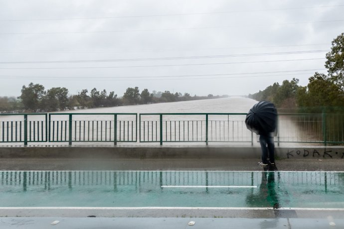 Una persona cruza el Puente de la Señorita de Camas bajo una intensa lluvia