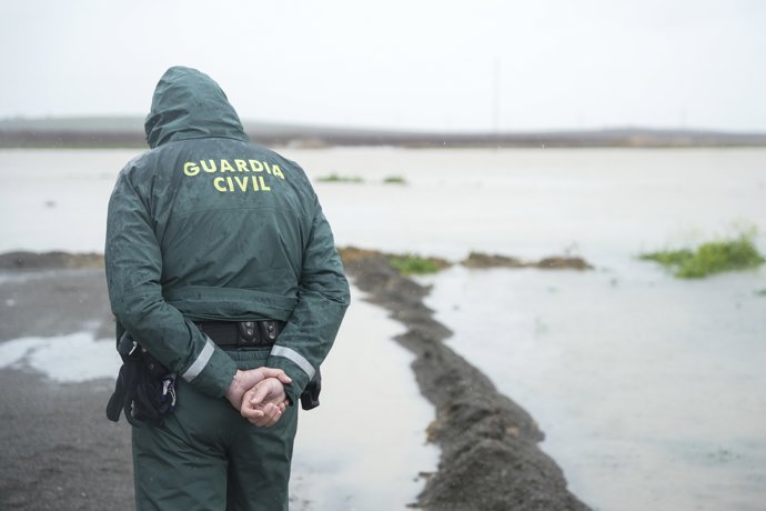 Un Guardia Civil en el lugar del desbordamiento en el Palmar de Troya la situación en el terreno tras el paso de las borrascas, a 7 de febrero de 2026 en Sevilla (Andalucía, España).