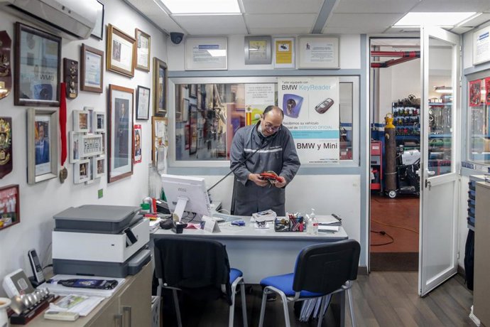 Archivo - Un trabajador responde al teléfono en talleres Otman, en el polígono industrial Ventorro del Cano en Alcorcón.