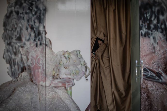 Archivo - 22 September 2021, Afghanistan, Kabul: An Afghan woman peeks out a beauty parlour where the outside advertisement is defaced. Images depicting women have been removed or covered up since the Taliban took control of the country. Photo: Oliver Wei
