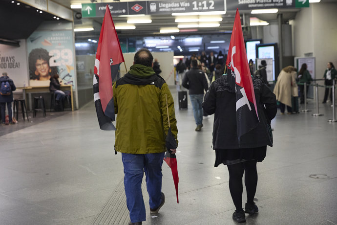 Dos personas llevan banderas de UGT durante la primera jornada de la huelga ferroviaria, en la estación de tren Madrid-Puerta de Atocha-Almudena Grandes, a 9 de febrero de 2026, en Madrid (España).