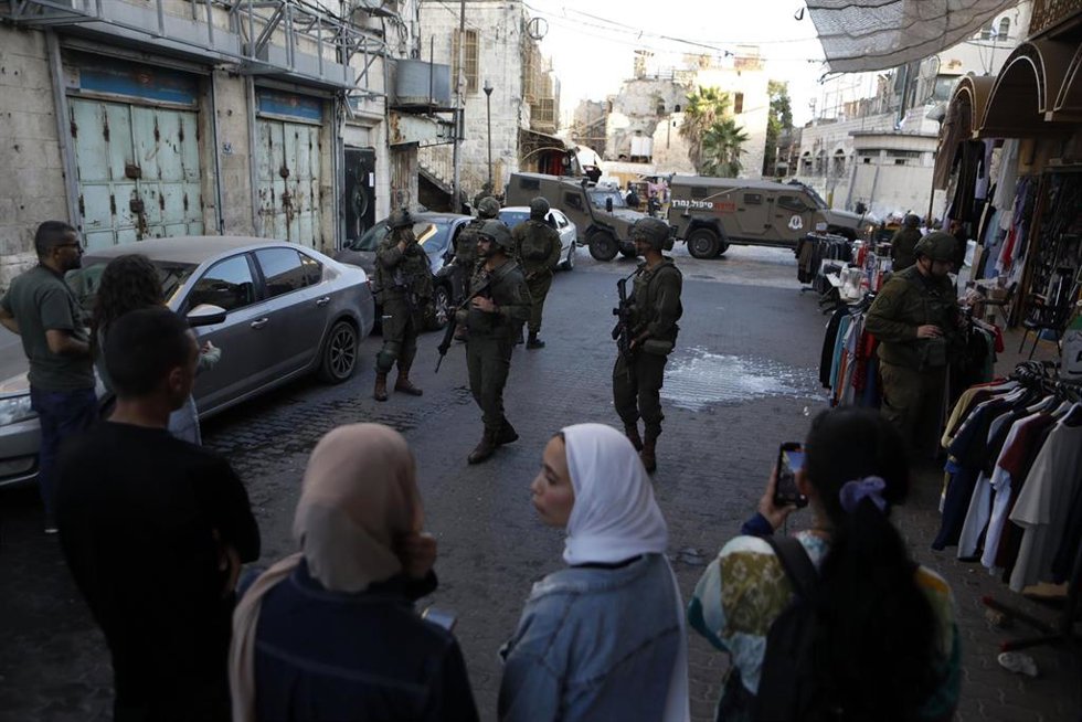 Archivo - Miembros de las fuerzas israelíes hacen guardia mientras colonos israelíes visitan una comunidad habitada mayoritariamente por palestinos en la ciudad de Hebrón, en Cisjordania