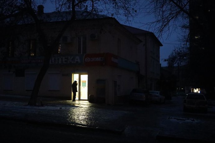 February 6, 2026, Odessa, Ukraine: A man stands in the light of a pharmacy on the dark, slender Nezhinskaya Street. Freezing rain fell in Odessa during the day - a dangerous atmospheric phenomenon in which precipitation instantly freezes upon contact with