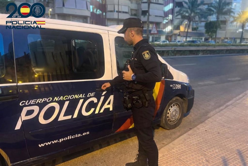 Un agente de la Policía Nacional junto a un vehículo.