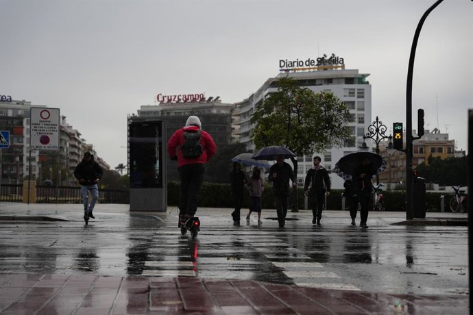 Peatones se protegen de la lluvia bajo sus paraguas, durante el paso de la borrasca Joseph. A 27 de enero del 2026 en Sevilla (Andalucía, España). El consejero de Sanidad, Presidencia y Emergencias de la Junta de Andalucía, Antonio Sanz, ha insistido este