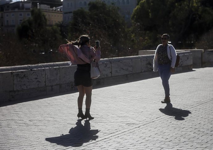 Archivo - Dos mujeres se hacen una fotografía mientras el viento les levanta la ropa y el pelo.
