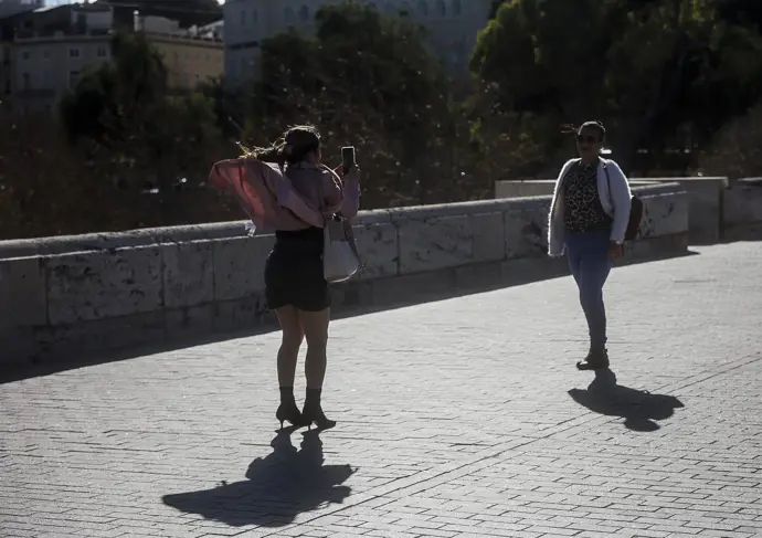 Mujeres fotografiándose mientras el viento levanta su ropa y pelo.
